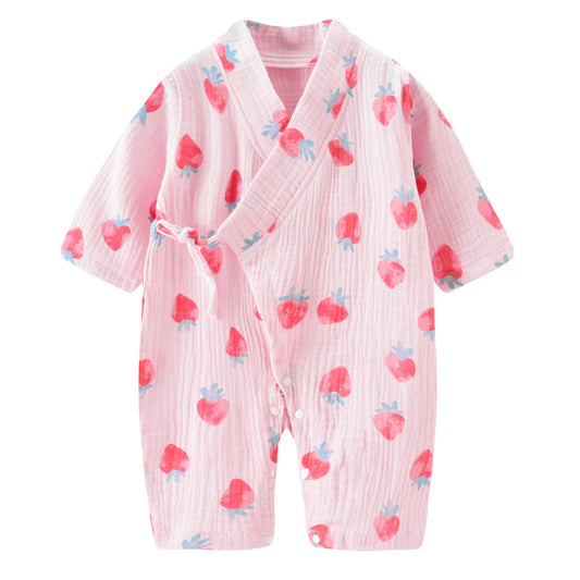 Pink baby romper with a wrap design, adorned with red and blue strawberry patterns. The lightweight fabric has a textured appearance, and features a side tie and buttons.