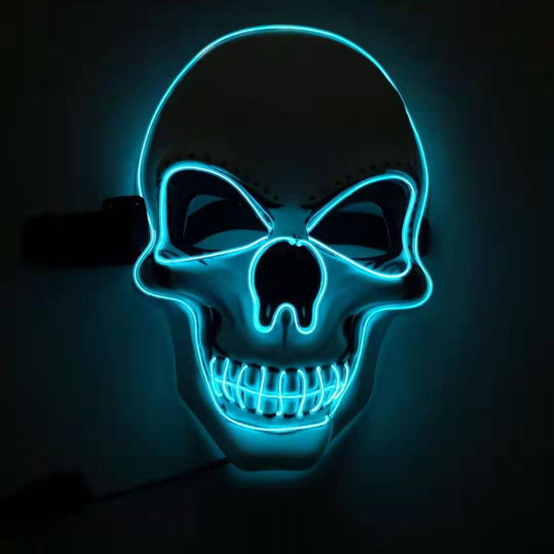 A glowing skull mask with neon blue outlines highlighting its features, including hollow eyes, nose cavity, and grinning teeth, set against a dark background.