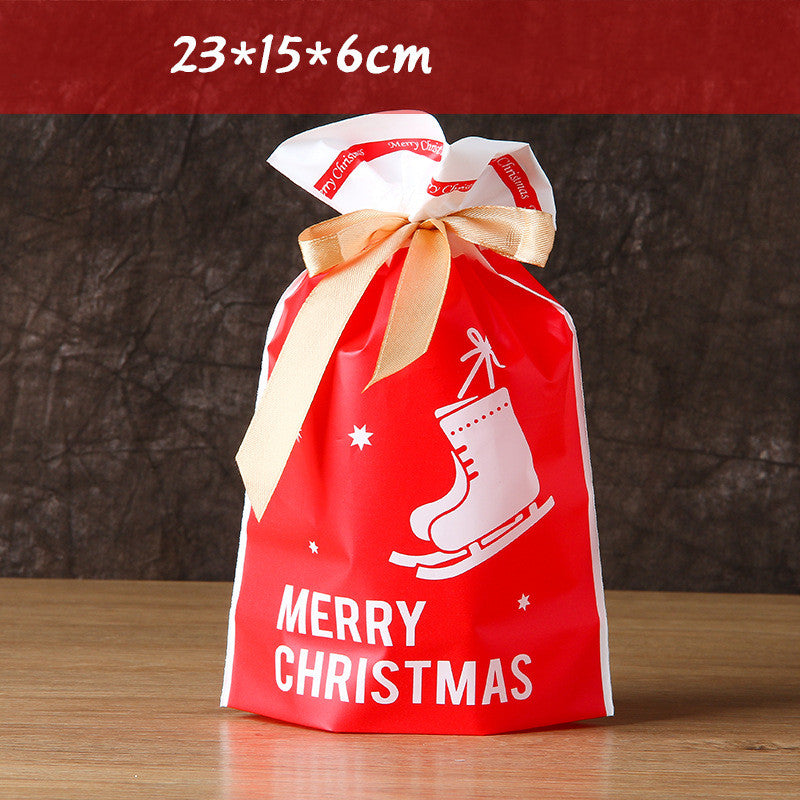 Red Christmas gift bag with skates graphic, "Merry Christmas" text, and beige ribbon. Dimensions noted as 23x15x6 cm. Placed on a wooden surface.