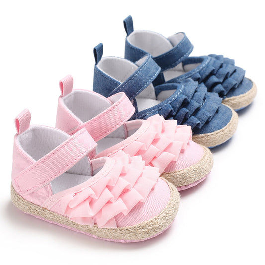 Two pairs of baby shoes displayed side by side; pink shoes with ruffled fronts and blue shoes with similar design, both featuring velcro straps and woven soles.