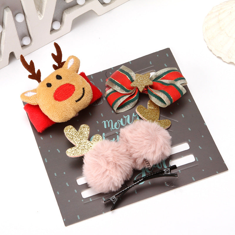 Festive hair clips on a card: a reindeer with red nose, a striped bow with gold star, and fluffy pink pom-poms with glitter antlers, against a dark card background.
