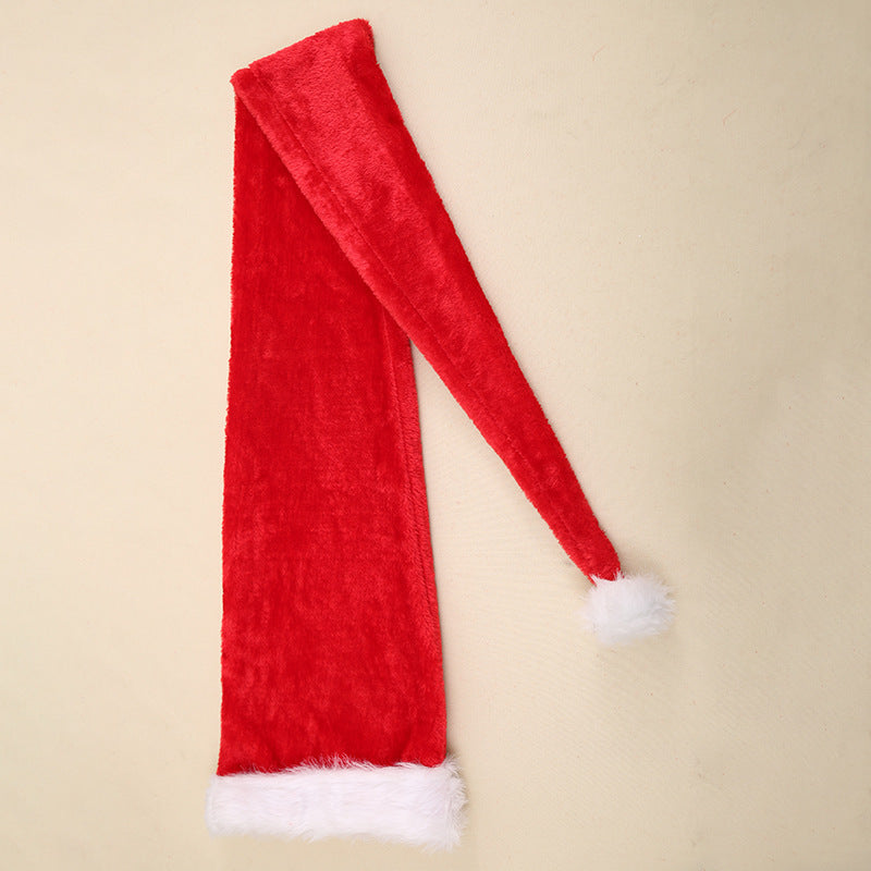 Long red velvet Christmas hat with white fur trim on both ends, laid flat on a light beige background.