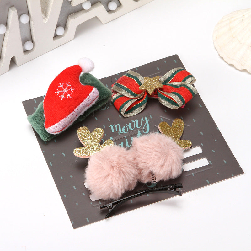 Festive hair accessories set includes a Santa hat clip, a red and green striped bow with a gold star, and reindeer antler clips with pink pom-poms on a "Merry Christmas" card.