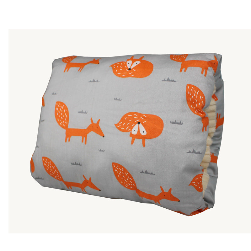 Gray pillow with cute orange fox illustrations in various playful poses. The pattern is repetitive and features small grass details in the background.