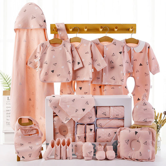 A collection of pink baby clothing and accessories with paper plane patterns, including shirts, onesies, bibs, towels, socks, and a hat, neatly displayed.