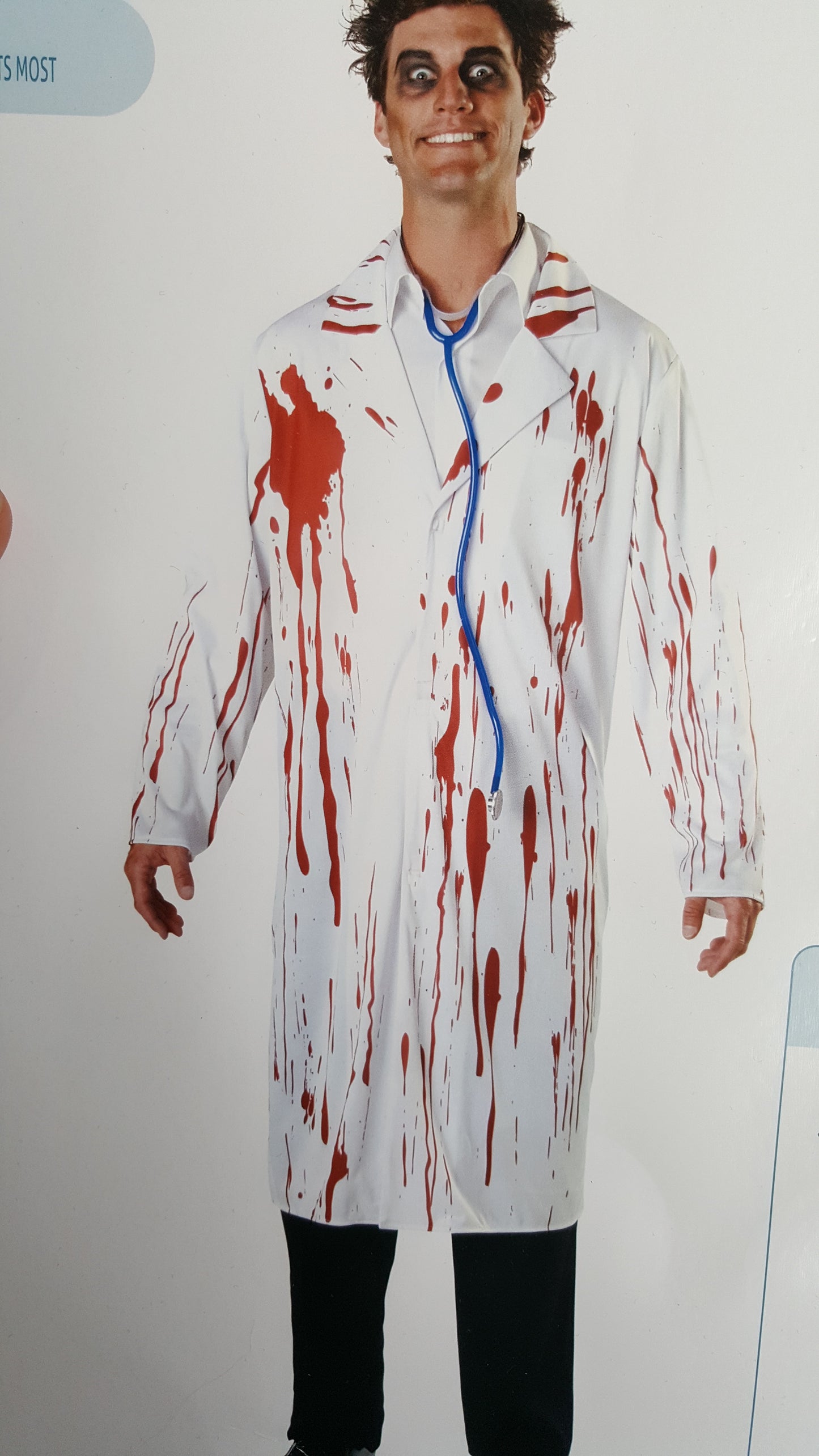 Man in a white coat splattered with red stains, wearing black eyeliner and a wide grin. A blue stethoscope hangs around his neck.