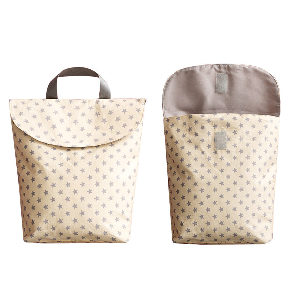 Two cream-colored bags with grey star patterns are shown: one closed with a handle, the other open, displaying its interior and velcro closure.