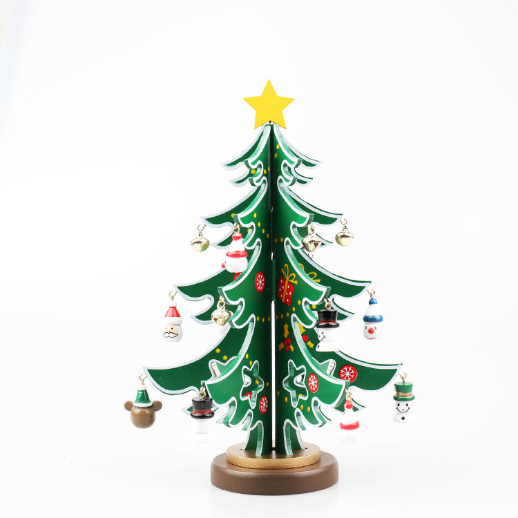 A small decorative Christmas tree with a yellow star on top, adorned with festive ornaments, including snowmen, bells, and Santas, sits on a round wooden base against a white background.