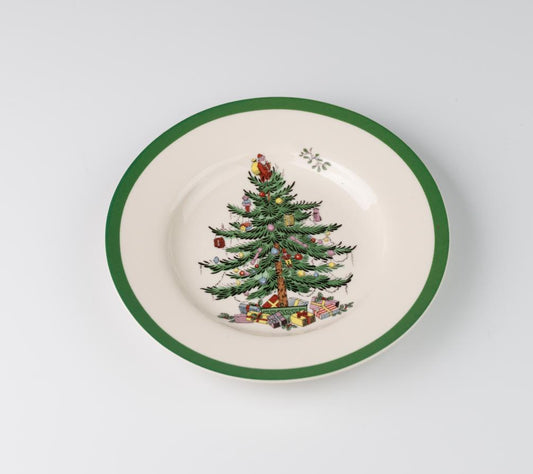 A porcelain bowl with a green rim features a decorated Christmas tree and presents. The tree is adorned with colorful ornaments and a golden star on top.