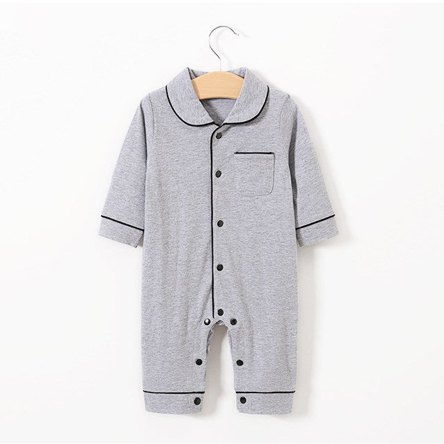 Gray baby romper with black piping, long sleeves, button closure, and a chest pocket on a wooden hanger against a white background.
