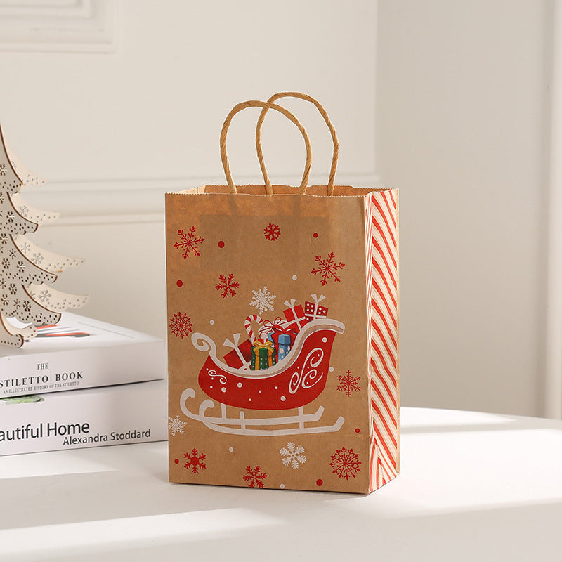 Brown gift bag with red sleigh design, filled with presents and surrounded by snowflakes. Candy cane-striped side. Placed on a white surface beside books and a wooden tree.