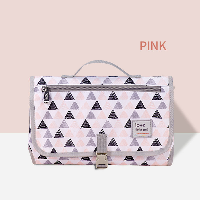 Pink geometric patterned bag with gray trim and handle. Features a front zipper pocket and a buckle clasp. Label reads "love little me." Text "PINK" is displayed above.