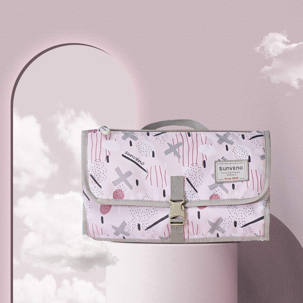Pink patterned bag with abstract designs, labeled "Sunveno," suspended against a pastel archway. Soft clouds and a minimalistic background enhance the elegant display.