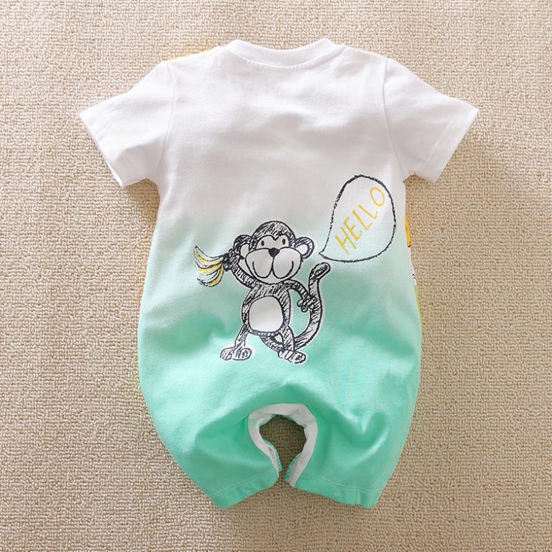 A baby romper with a cute monkey graphic saying "HELLO" in a speech bubble. The romper is white and turquoise, lying flat on a beige textured surface.