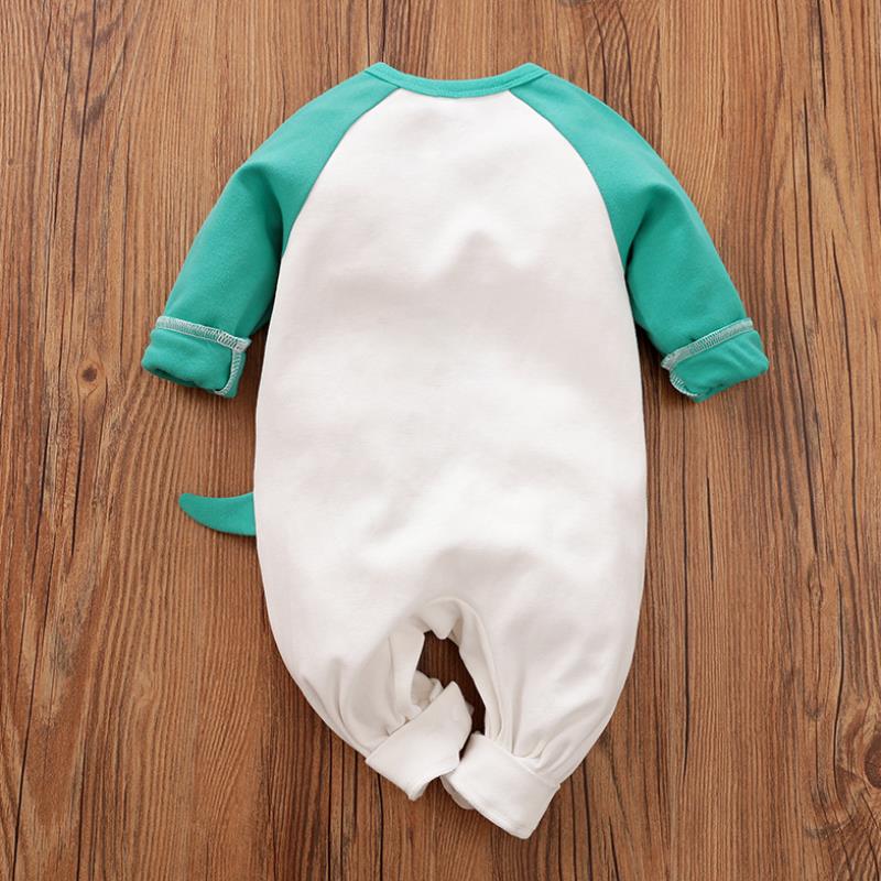 Baby romper lying on wooden floor; features green sleeves and white body, plus a small, playful tail on the back.