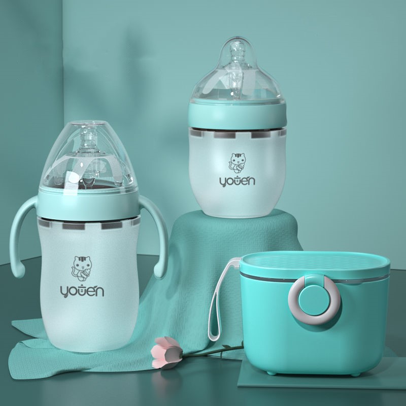 Three pastel-colored baby bottles and a matching container are displayed on a soft blue surface, adorned with a small flower.