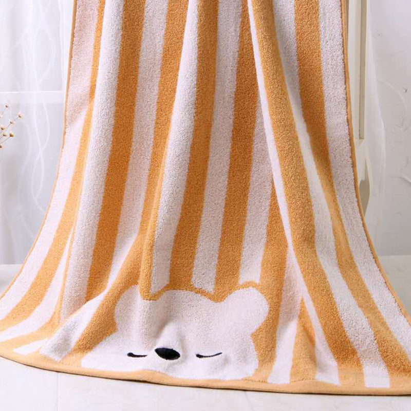 A cozy blanket with vertical orange and white stripes features a cute, sleepy bear face at the bottom. It hangs softly, suggesting warmth and comfort.