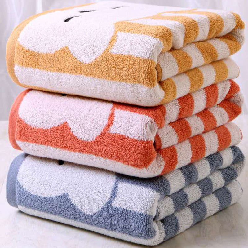 A stack of three folded towels with cloud patterns in yellow, orange, and blue hues, placed on a light surface. Each towel features bold stripes on the sides.