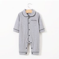 Gray infant romper with black piping, featuring a collared neckline, front pocket, and snap buttons. It hangs on a wooden hanger against a white background.