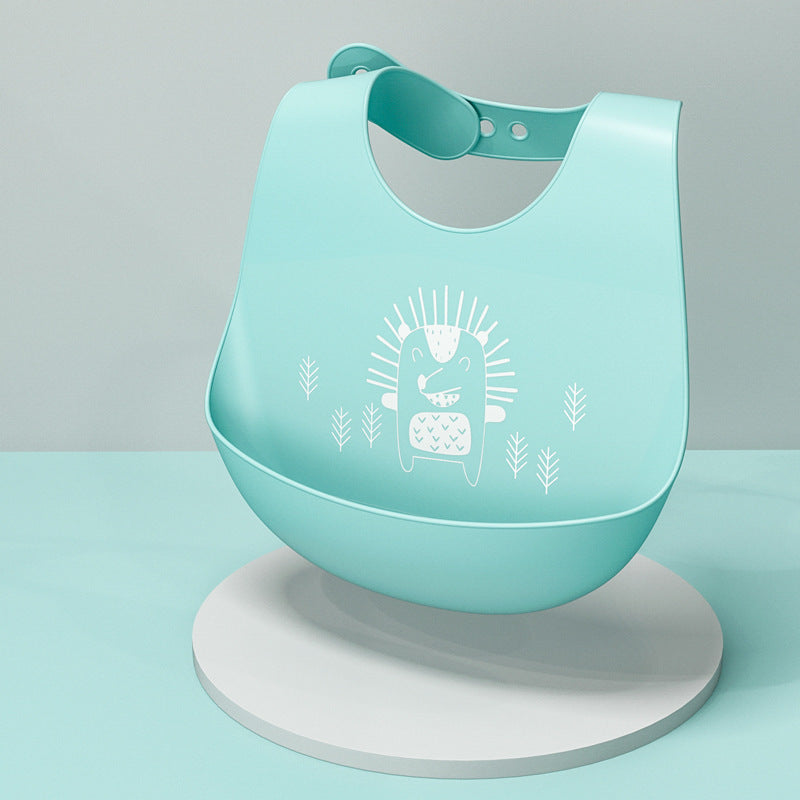 A turquoise silicone bib with an illustrated white hedgehog design is displayed on a circular white pedestal against a matching turquoise background.