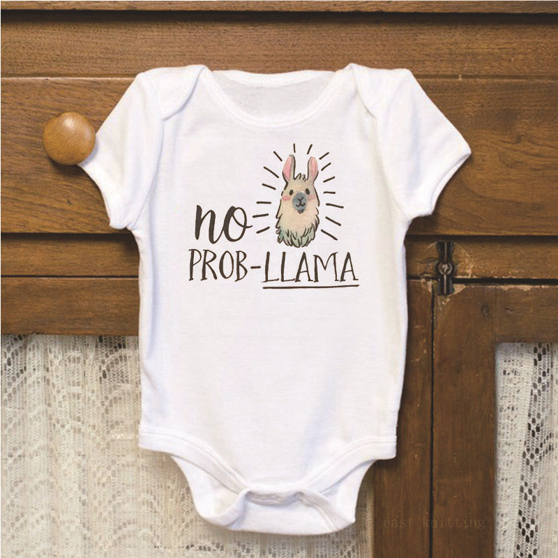 White baby onesie with illustrated llama and the text "No Prob-Llama" in playful font, displayed on a wooden surface with lace fabric underneath.