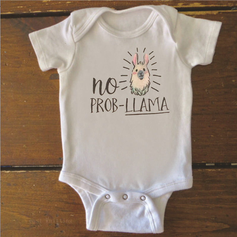 White baby onesie on a wooden surface with a cute llama illustration and the text "no prob-llama" printed on the front.