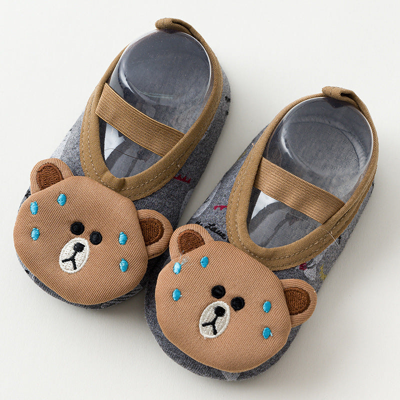 Gray children's slippers with brown straps, featuring cute bear faces embroidered on the toes. The bears have blue and white details, creating a playful design.