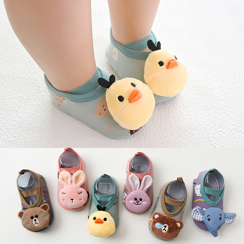 Baby wearing green socks with plush yellow chicks on toes. Below, a display of six colorful baby socks featuring animal designs like bears, bunnies, and an elephant.