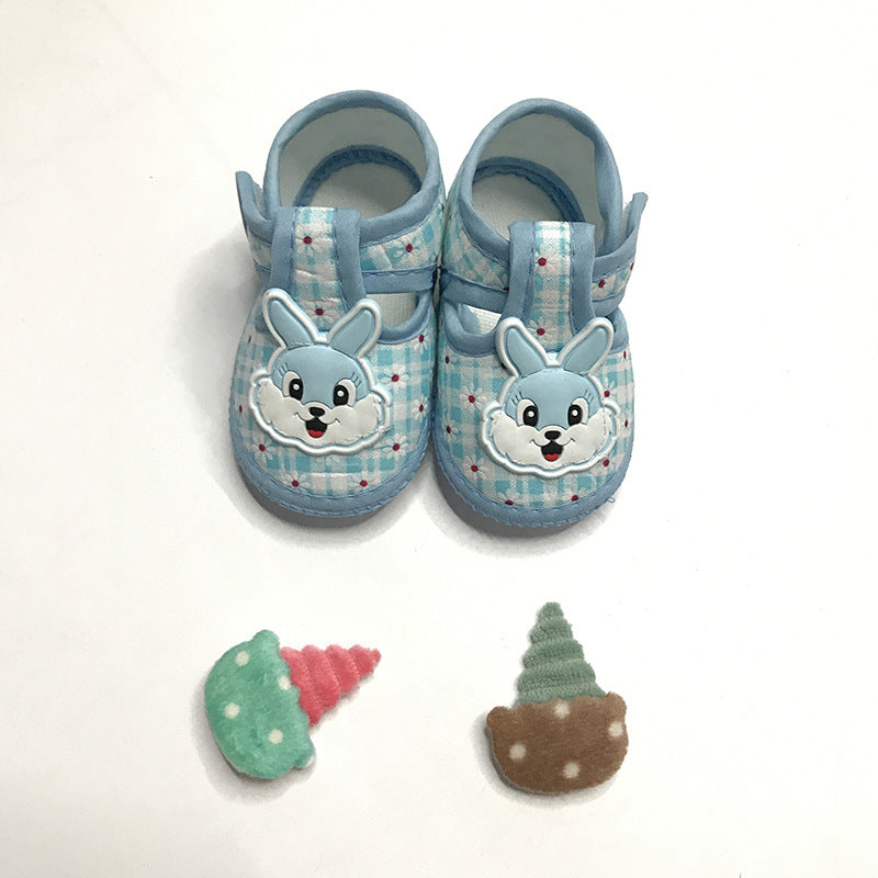 Blue plaid baby shoes with bunny faces on top, placed above two fabric ice cream cone patches in green and pink, and green and brown, on a white background.