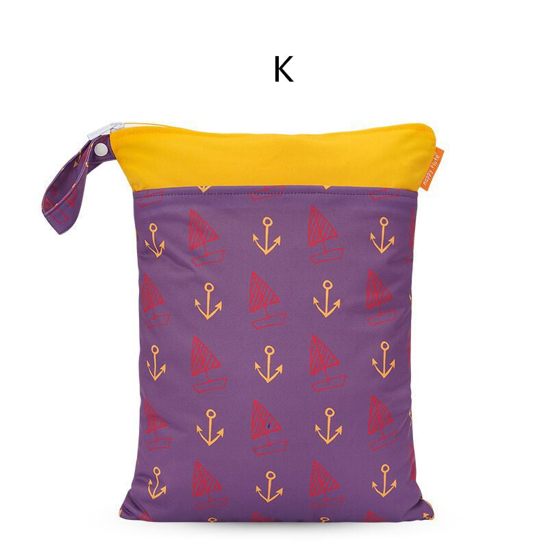 Purple zippered pouch with yellow top, featuring red sailboats and yellow anchors. Attached loop on the side for carrying. White backdrop with a black letter "K" above.