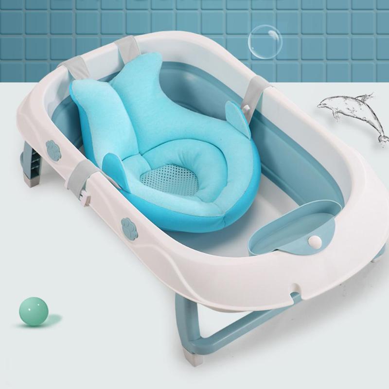 A white and blue collapsible baby bathtub with an ergonomic blue cushion insert, surrounded by playful bubbles and a dolphin graphic against a blue-tiled background.
