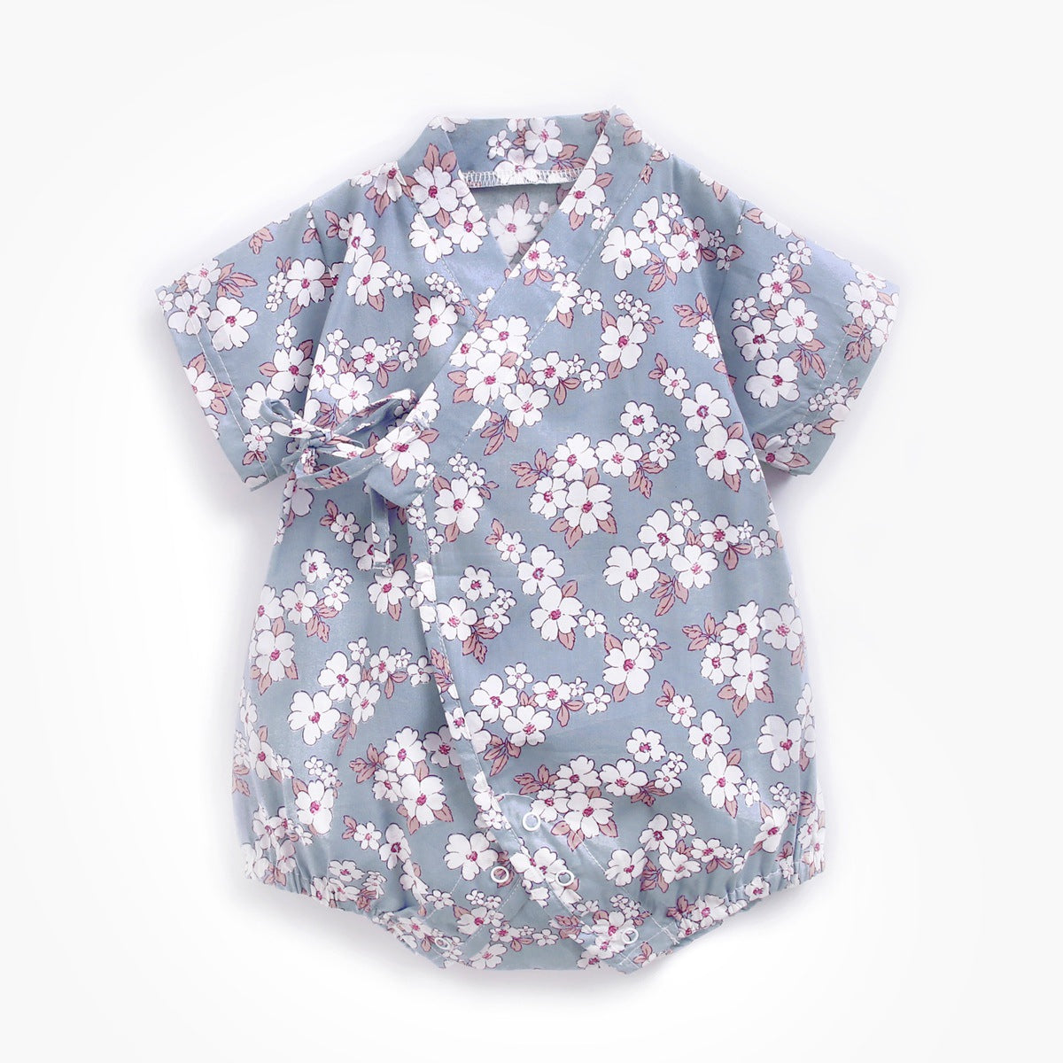A baby romper with a blue background featuring a pink and white cherry blossom floral pattern. It has short sleeves and a side tie closure.