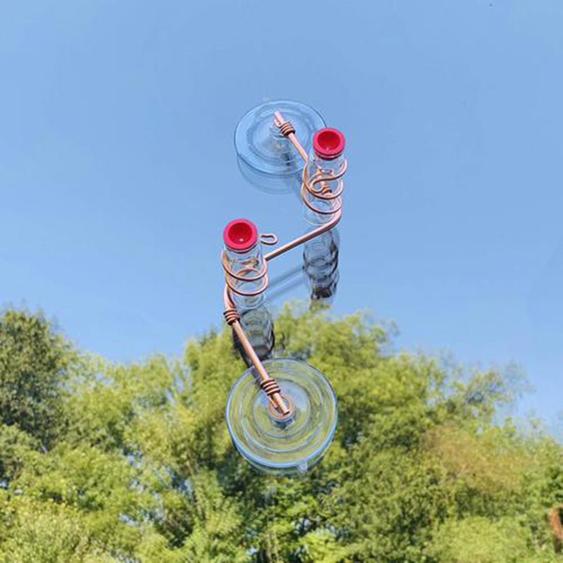 A creative perspective shows two upside-down suction cups with coils and red-tipped tubes against a clear blue sky and green foliage in the background.
