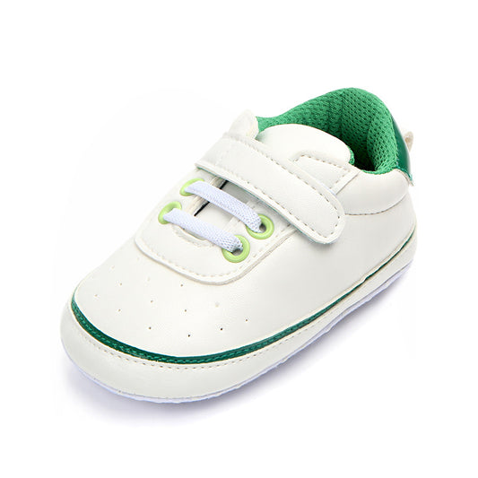 White baby shoe with a green interior and accents, featuring a hook-and-loop strap, white laces, and green eyelets. Simple design with a soft sole for infants.