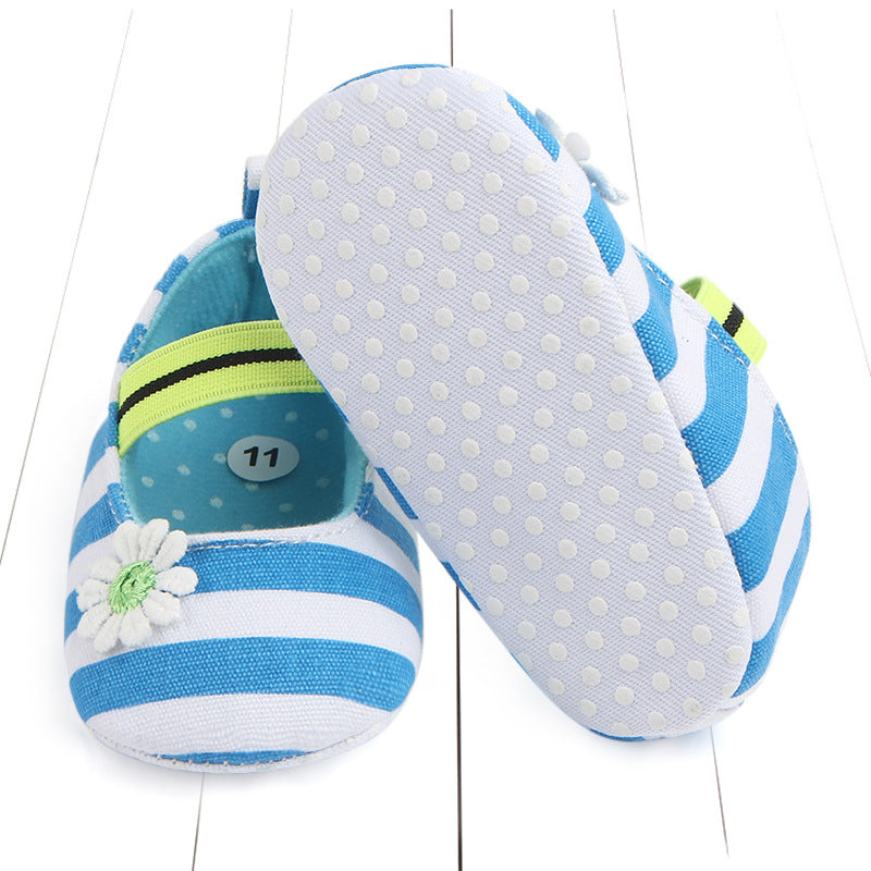 Blue and white striped baby shoes with daisies and a green elastic band. One shoe is upright showing a polka dot sole. The inside is light blue with a size 11 sticker.