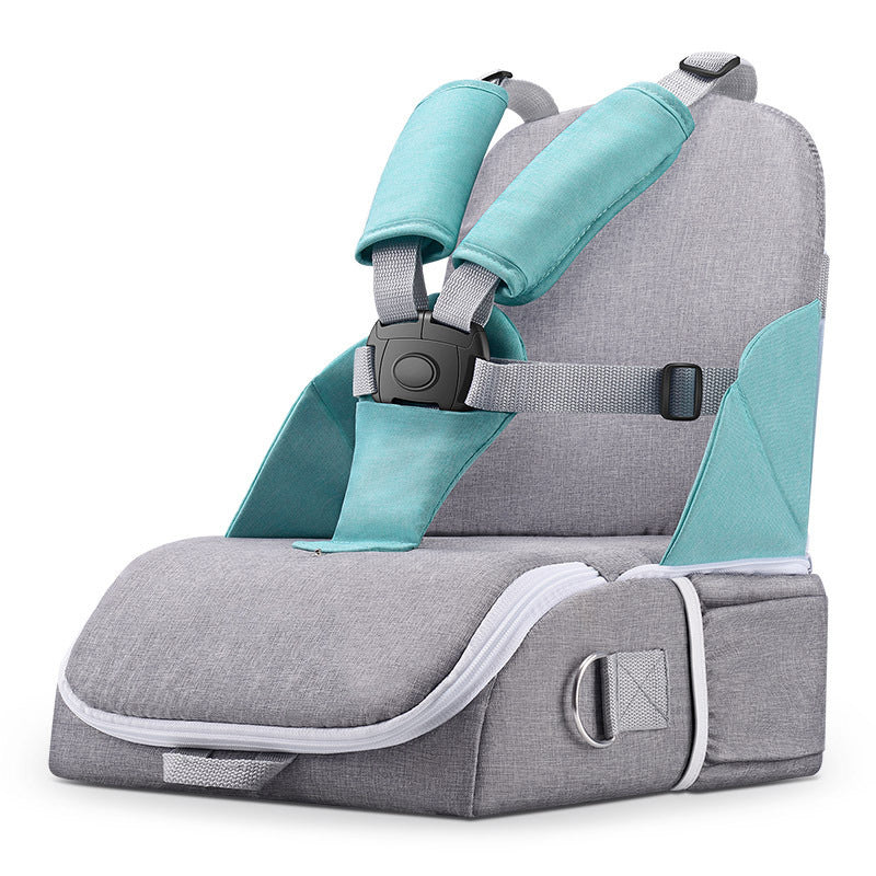 Gray and teal portable child safety seat with padded harness. Features an adjustable strap, buckle, and soft cushion. Designed for secure seating in various settings.