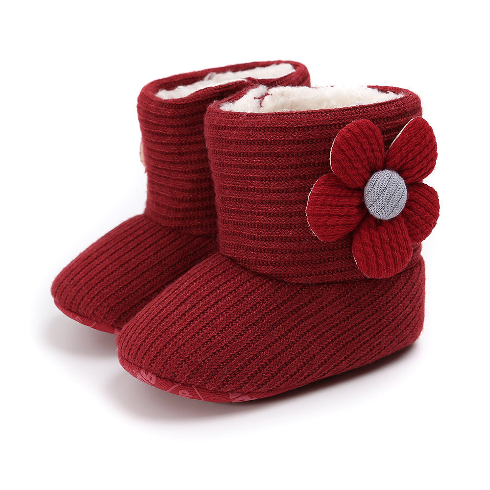 Cozy red baby boots with ribbed knit texture and plush white lining. Each boot features a decorative fabric flower on the side.