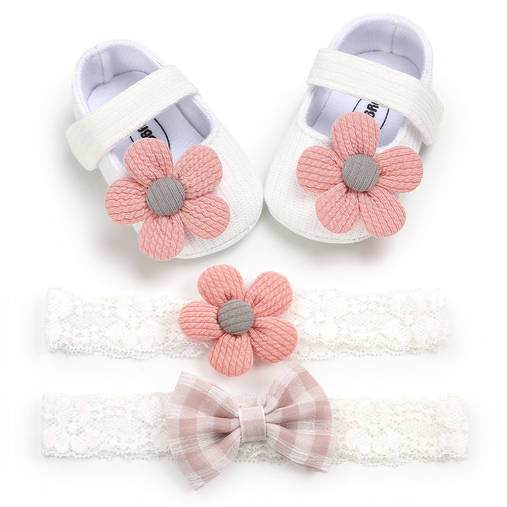 White baby shoes with pink knitted flowers, paired with matching lace headbands. One headband has a pink flower, the other a pink-checkered bow.