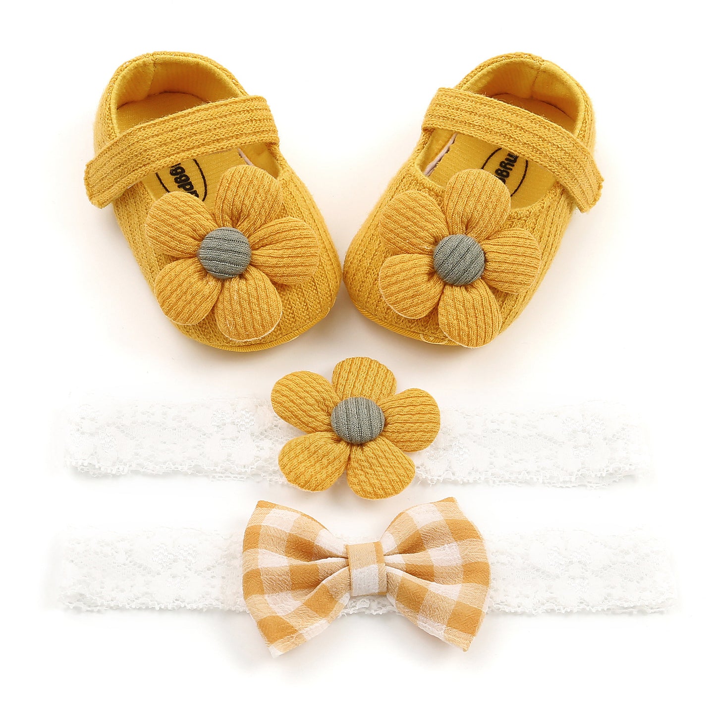 Yellow baby shoes with fabric flowers, accompanied by a matching flower headband and a gingham bow headband, all set on a white background.