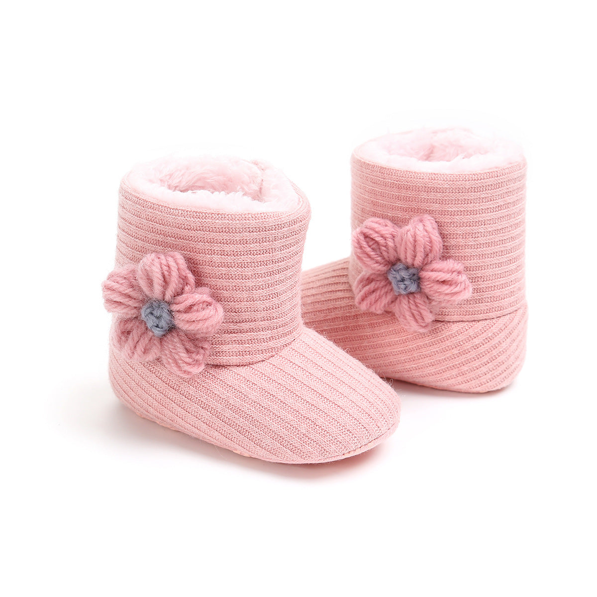 Pink baby booties with ribbed texture and soft interior, adorned with knitted flowers on the side.