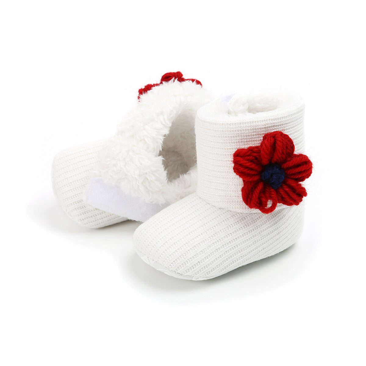 White knitted baby booties with fluffy interiors, adorned with red yarn flowers on the sides. The texture appears soft and warm, suitable for infants.