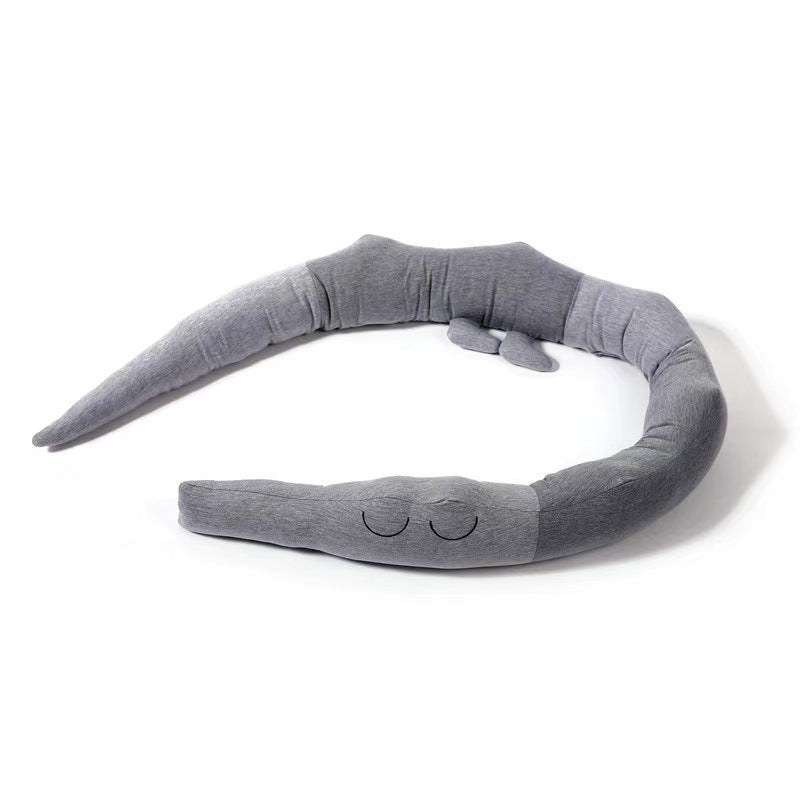 Gray plush snake-shaped pillow with closed embroidered eyes, coiled in a circle on a white background. The pillow appears soft and segmented.