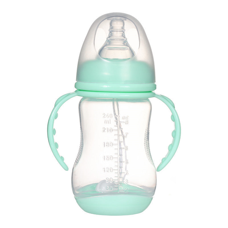 Transparent baby bottle with mint green handles and lid, featuring volume markings on the side. The nipple is enclosed under a clear protective cover.