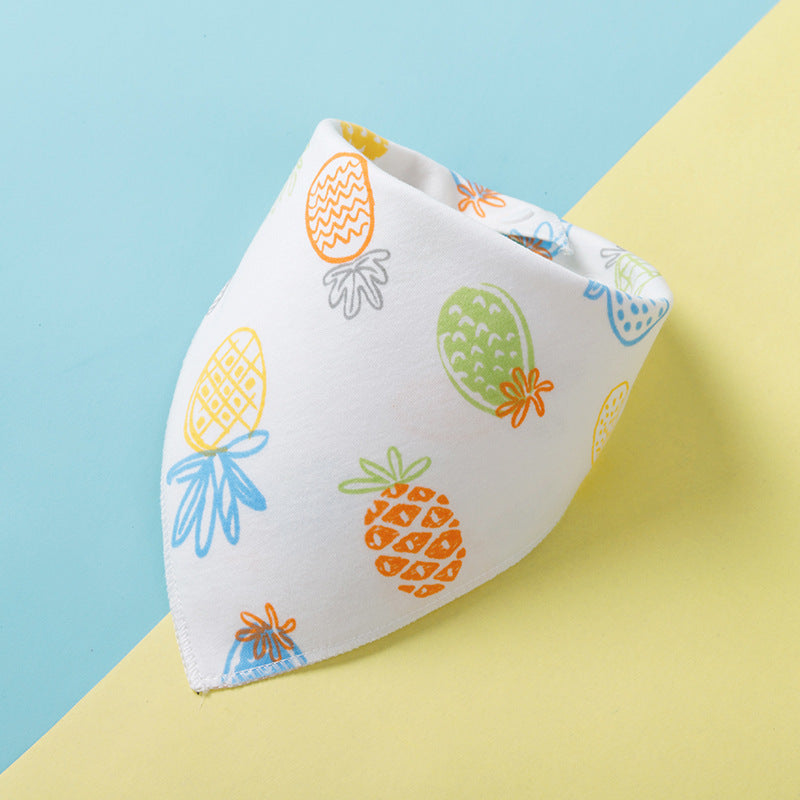 White fabric with colorful pineapple prints, including orange, green, blue, and yellow, folded neatly on a pastel blue and yellow background.