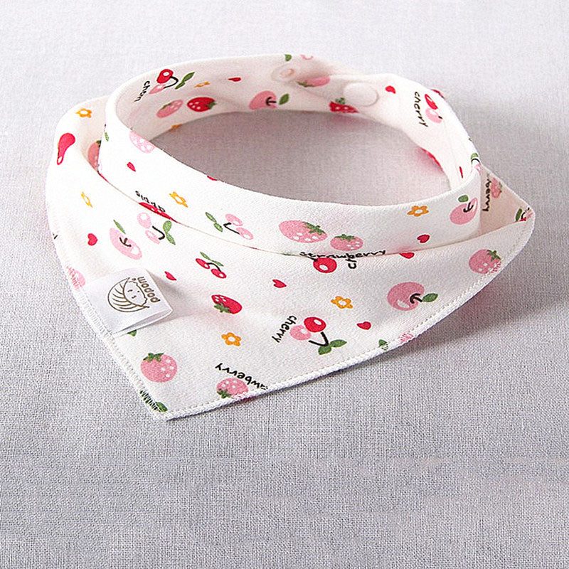 A white cotton bib with colorful fruit and flower patterns, featuring strawberries, cherries, and small flowers, displayed on a light fabric background.