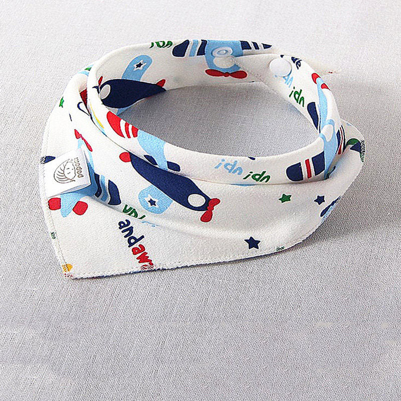 White baby bib with colorful airplane patterns, blue stars, and playful text. The bib is folded on a light gray surface, featuring a logo tag on one side.