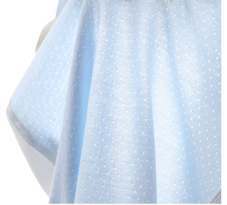 Close-up of a light blue fabric with a subtle dotted pattern and stitched edge, draped smoothly, capturing the delicate texture and gentle folds.