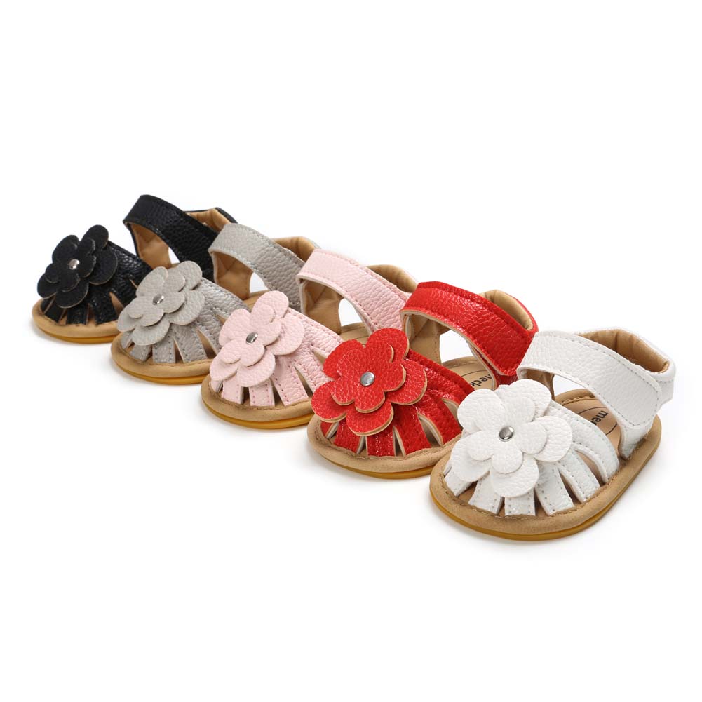 Five pairs of baby sandals in black, grey, pink, red, and white. Each pair features a decorative flower on the front, with a soft sole and an open toe design.