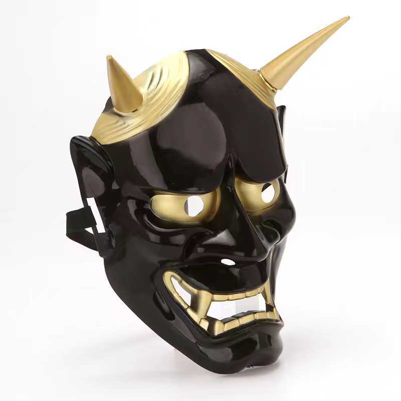 Black and gold demonic mask with two pointed horns, wide grin, and hollow eyes. The design is glossy, accentuating the dramatic and theatrical elements.