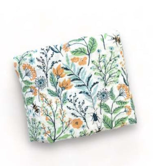 Folded fabric with a vibrant botanical print, featuring green leaves, orange flowers, and insects on a white background.